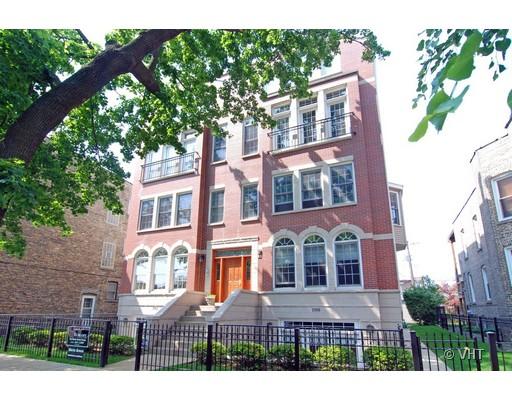 Front view of a multi-story brick building with large windows and stairs leading to the entrance.