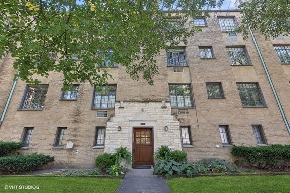 Front view of a multi-story brick building with an entrance door and several windows.