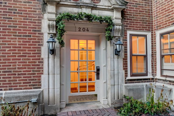 Front view of a brick building entrance with a decorative door and lanterns.