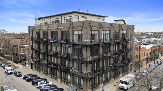 Front view of a multi-story building with balconies and large windows.