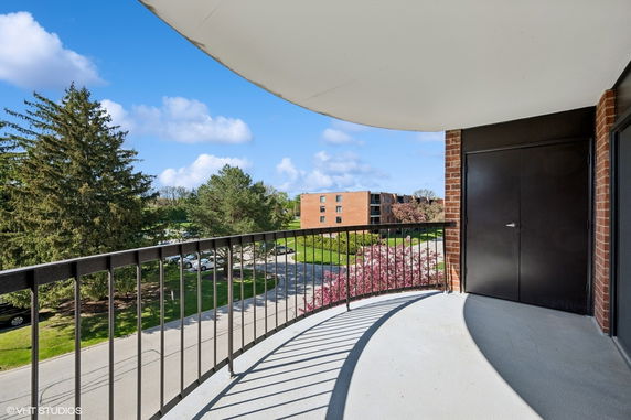 Balcony view overlooking surrounding area with trees and distant buildings.