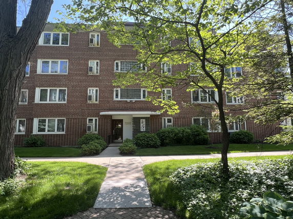Front view of a multi-story brick apartment building with multiple windows.
