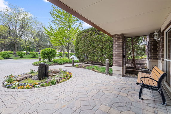 Entrance area of a building with a bench and paver walkway.