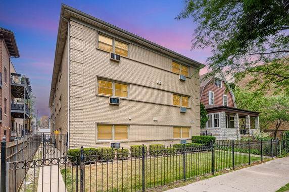 Front view of a three-story brick residential building with air conditioning units.
