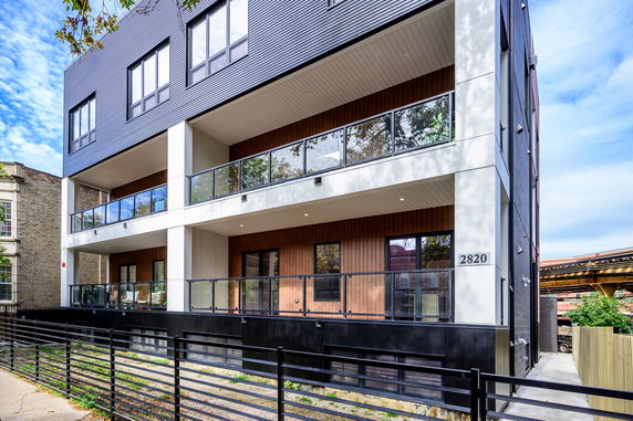 Front view of a modern multi-story building with large windows and balconies.
