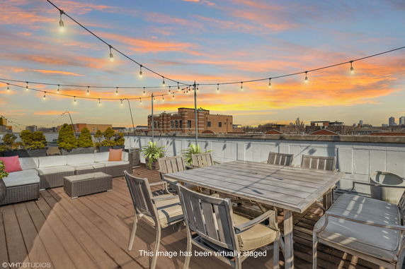 Rooftop patio with seating area and string lights at sunset.