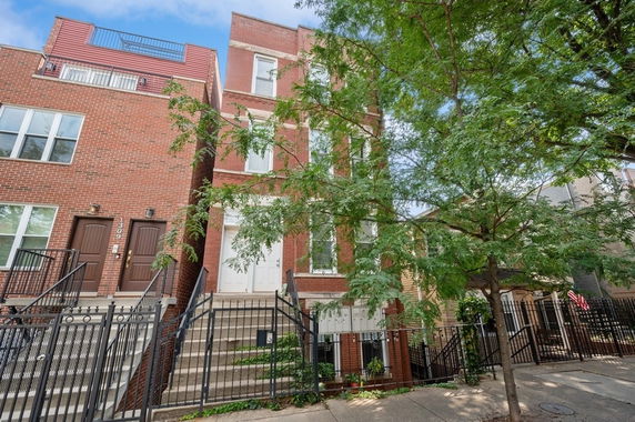 Front view of a multi-story brick building with staircases leading to entrances.