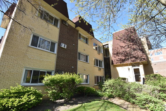 Front view of a multi-story apartment building with yellow and brown brick exterior.