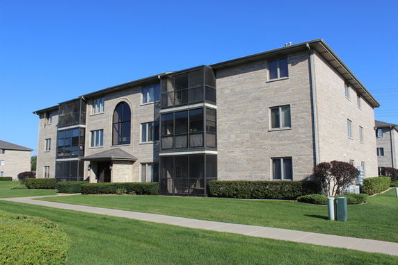 Front view of a three-story apartment building with multiple windows and a central entrance.