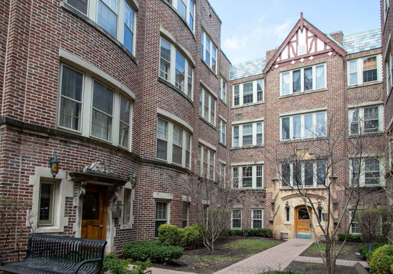 Front view of a multi-story brick apartment building with decorative windows and entrances.