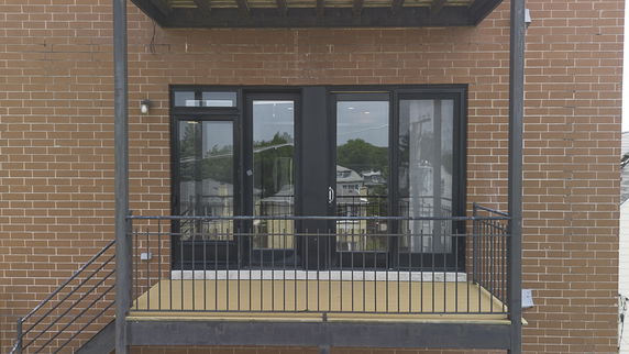 Front view of a building with a small balcony and glass doors on a brick facade.