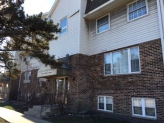 Front view of a multi-story residential building with brick and siding exterior.