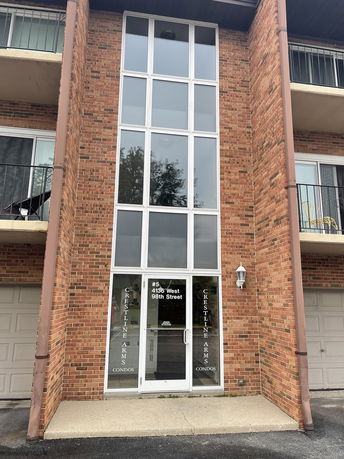 Front view of a multi-story brick building with a central glass entryway.