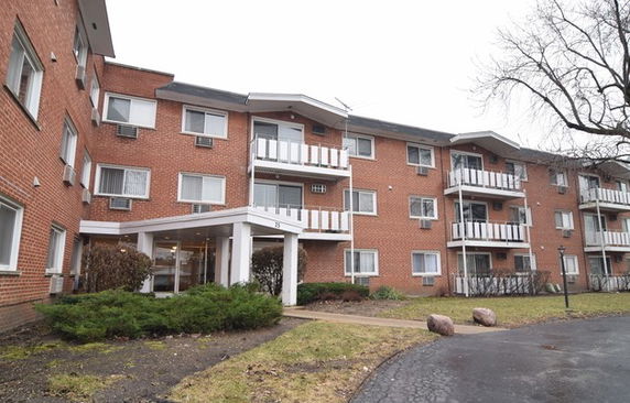 Front view of a multi-story brick apartment building with balconies.
