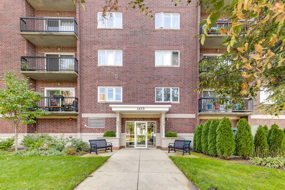Front view of a multi-story brick apartment building with balconies.