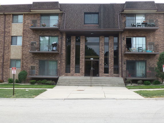 Front view of a multi-story brick apartment building with balconies.
