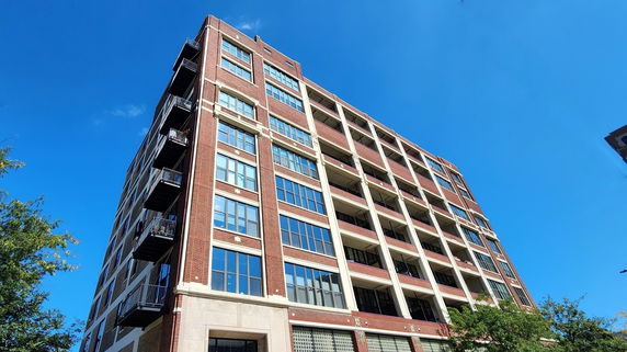 Front view of a multi-story brick building with numerous windows and balconies.