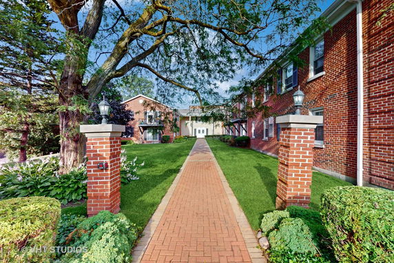 Front view of a brick house with a walkway and greenery.