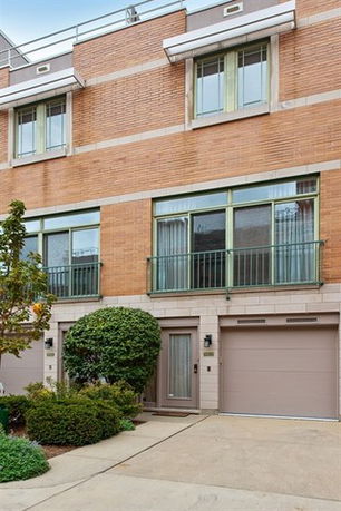 Front view of a multi-story townhouse with large windows and garage doors.