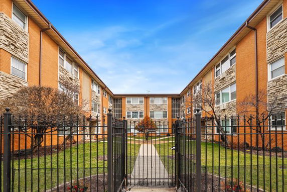 Front view of an apartment building with a gated entrance.