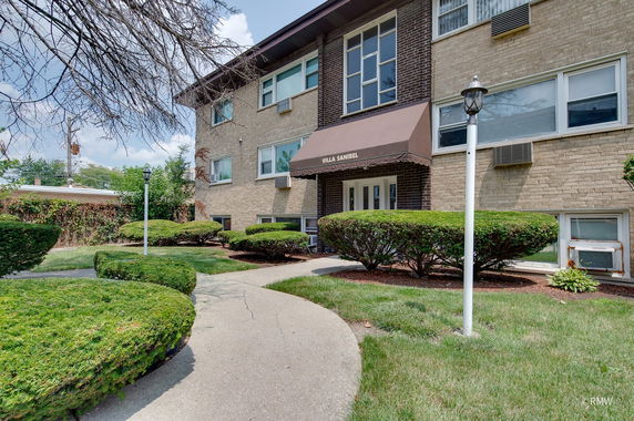 Front view of a brick mid-rise residential building with an awning over the entrance.