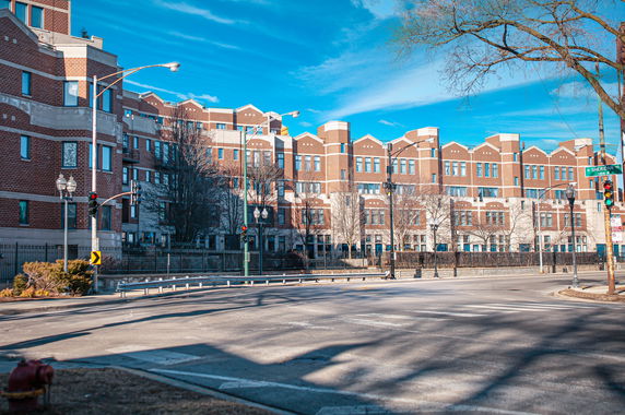 Front view of a multi-story brick building with multiple windows and decorative elements.