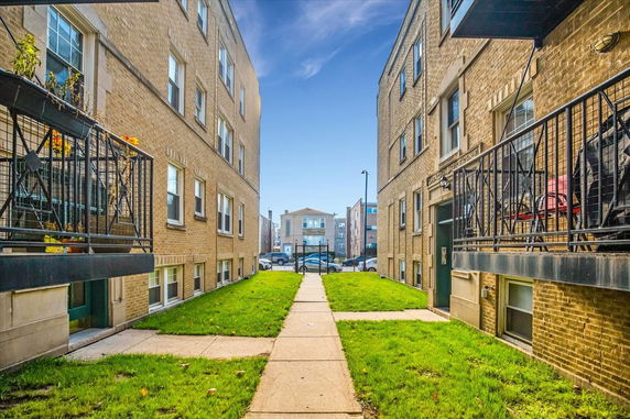 View between two buildings with a pathway leading to a building in the distance.