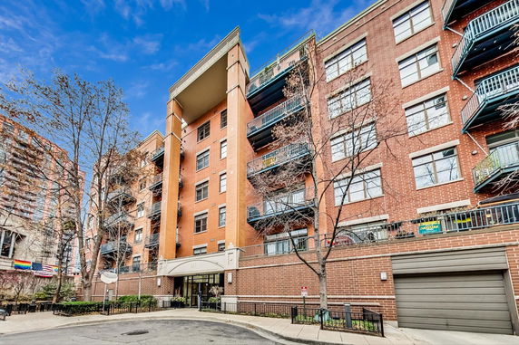 Front view of a multi-story brick apartment building with balconies.