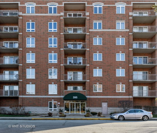 Front view of a multi-story brick apartment building with balconies.