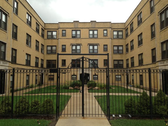Front view of a multi-story apartment building with a gated entrance.