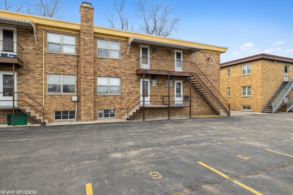 Front view of a two-story brick apartment building with exterior staircases.
