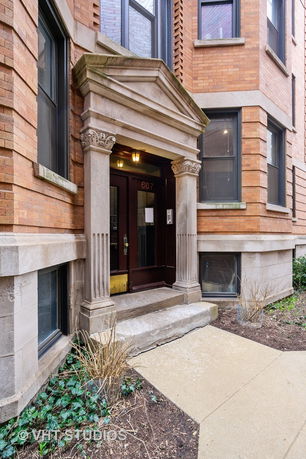 Front view of a building entrance with decorative columns and brick exterior.
