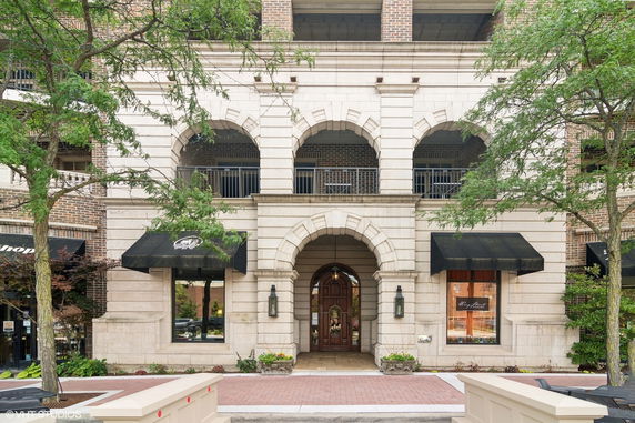 Front view of a building with stone arches and black awnings.