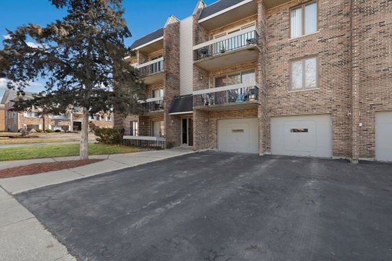 Front view of a multi-story brick building with balconies and garage doors.