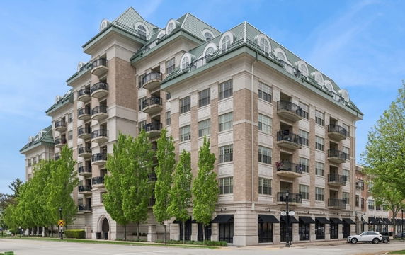 Front view of a multi-story residential building with balconies and unique roof design.