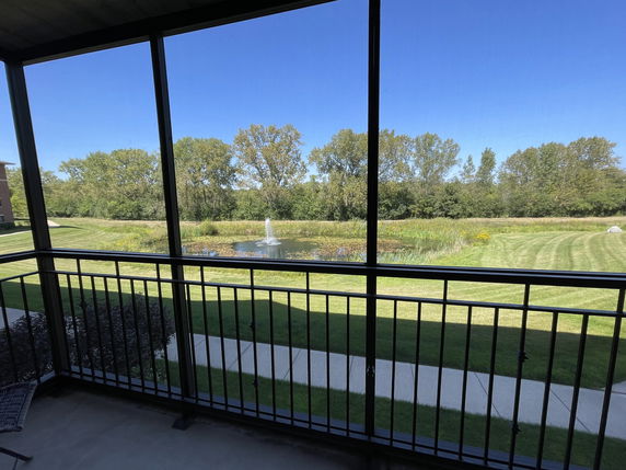 View from a balcony overlooking a landscaped area with a fountain and trees.