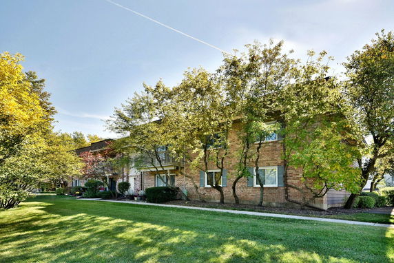 Front view of a two-story brick building with large windows, surrounded by trees and a grassy area.