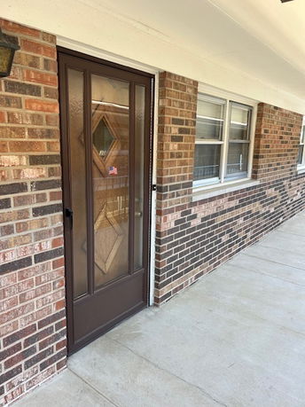 Front view of a brick house with a glass door and windows.