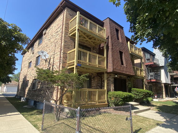 Front view of a brick apartment building with multiple balconies.