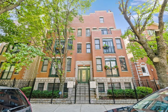 Front view of a multi-story brick building with a gated entrance.