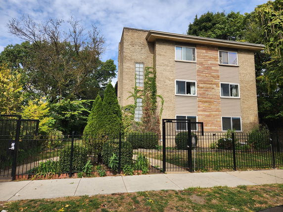 Front view of a multi-story residential building with a brick and stone facade.