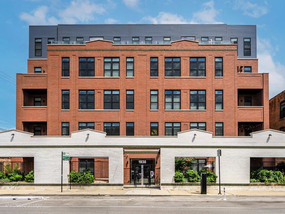 Front view of a multi-story brick building with large windows and balconies.