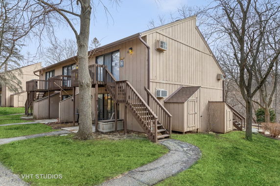 Front view of a two-story house with outdoor stairs and wooden siding.