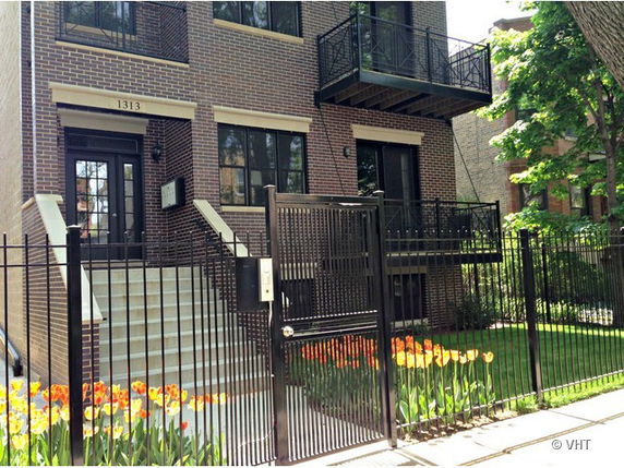 Front view of a multi-story brick building with a gated entrance.