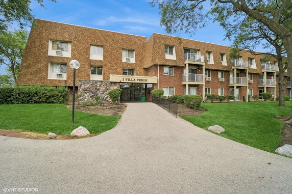 Front view of a three-story apartment building with multiple balconies.