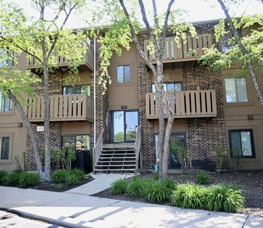 Front view of a three-story apartment building with brick and wood siding and multiple balconies.