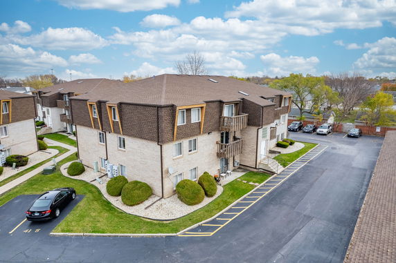 Front view of a multi-story residential building with brown roofing and brick exterior.