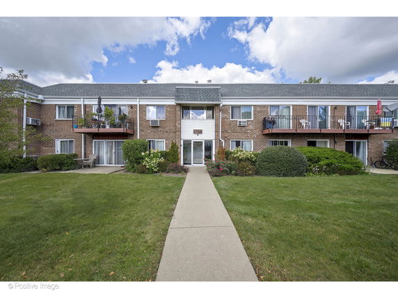 Front view of a two-story apartment building with balconies and a central entrance.