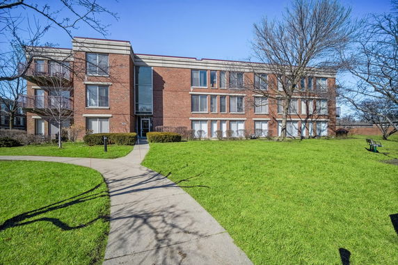Front view of a multi-story brick building with large windows and balconies.