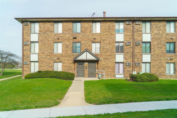 Front view of a three-story brick apartment building with several windows and a central entrance.